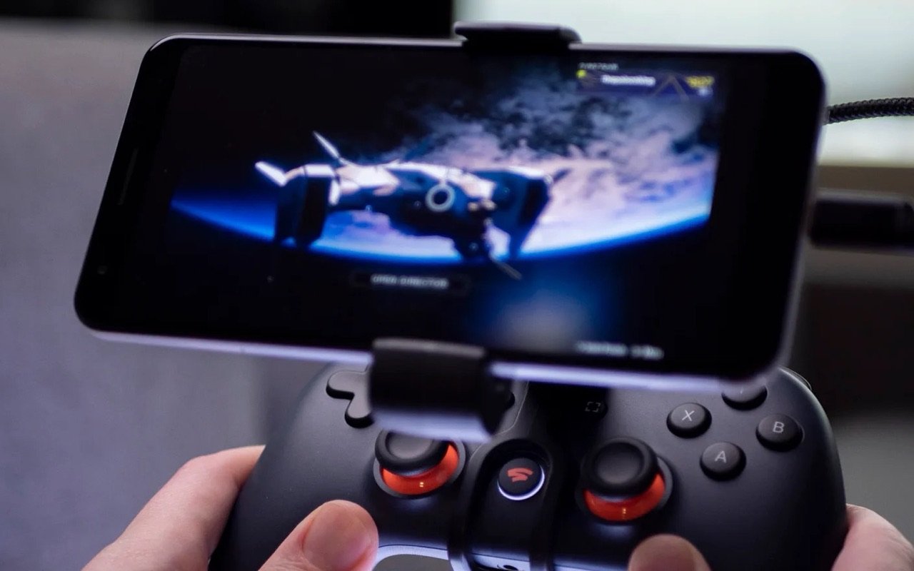 Destiny 2 streaming on Stadia: a phone clipped to a Stadia controller shows a ship in orbit above a planet.